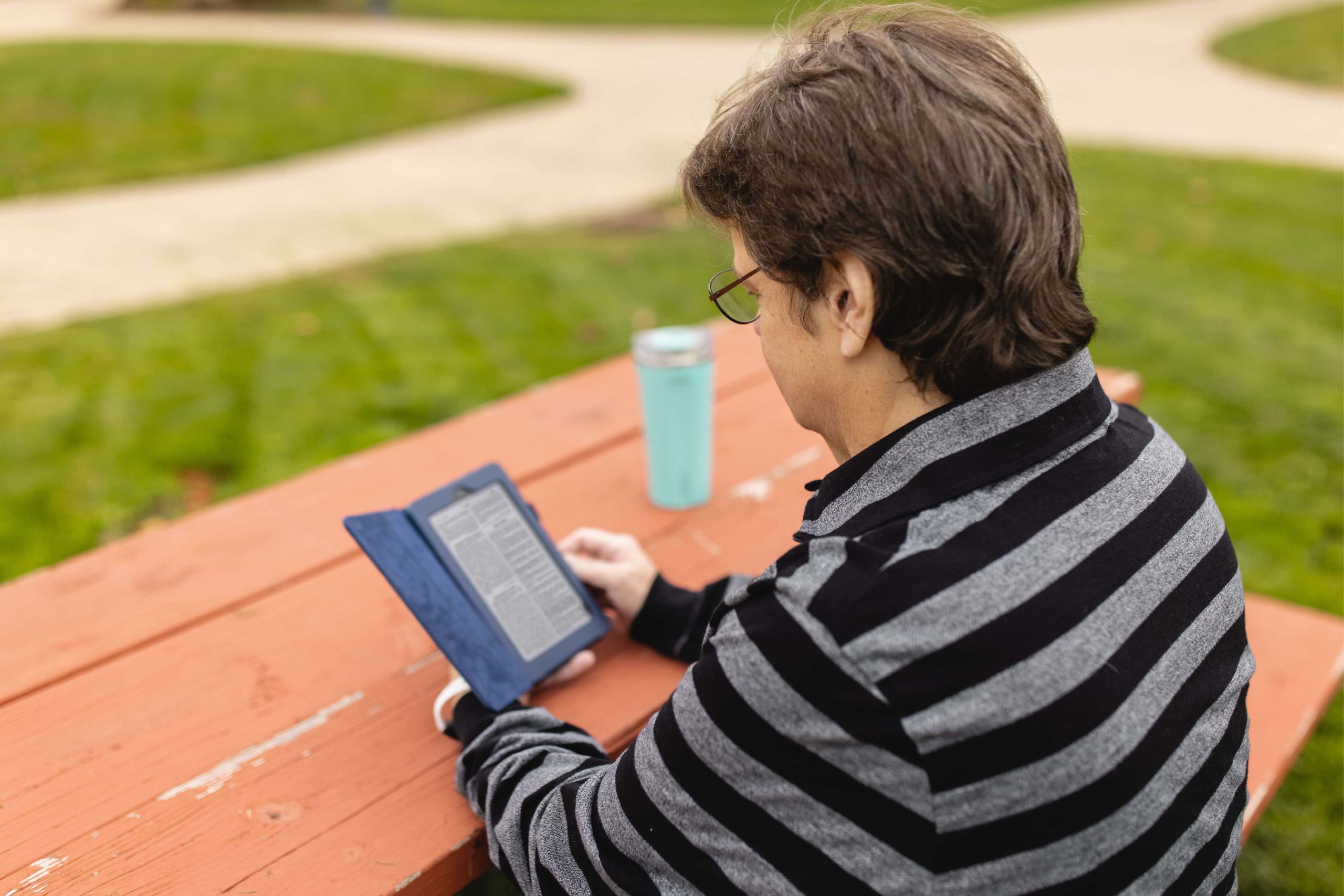 student sitting outside reading an e-book